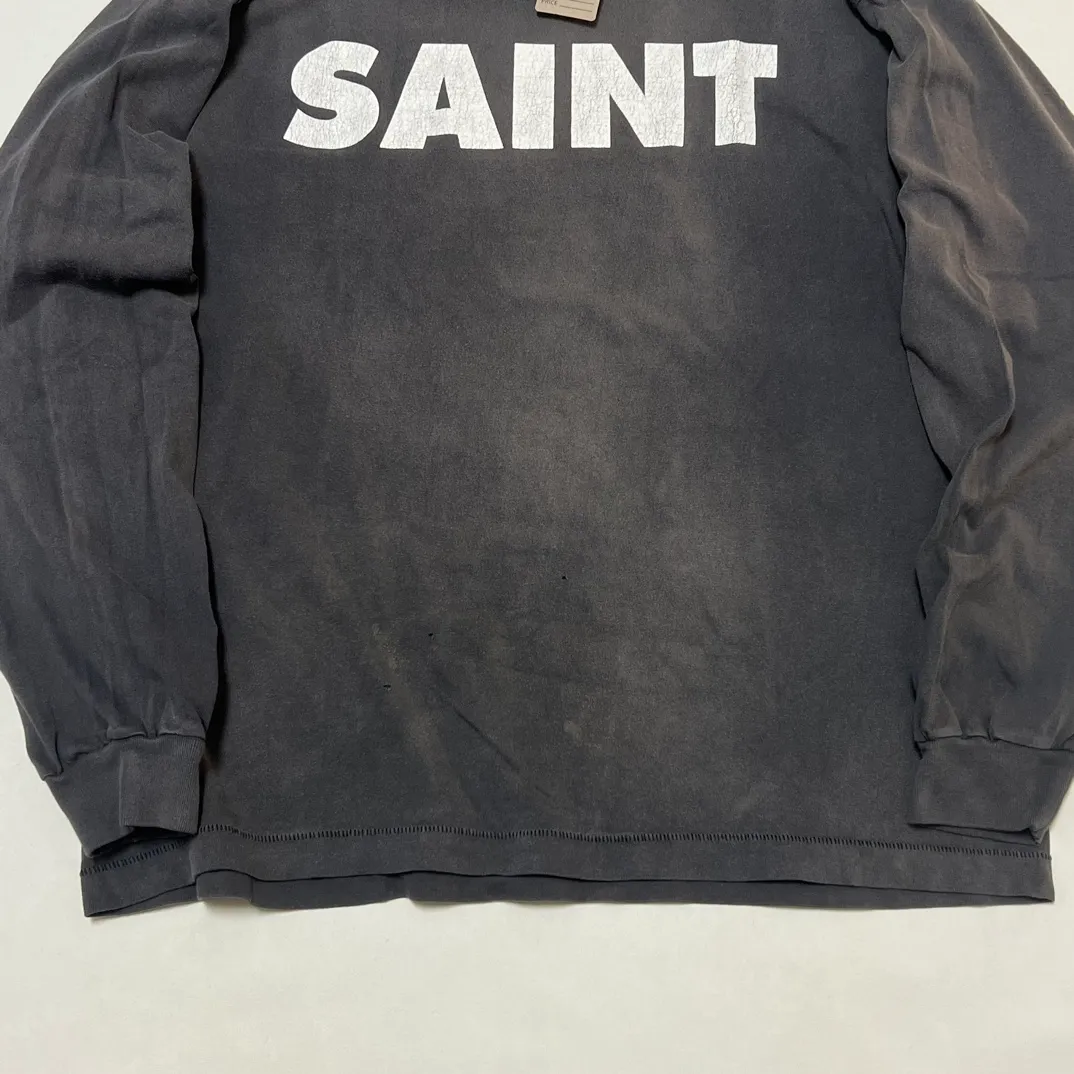 SAINT Mxxxxxx S>N>T LS TEE/BLACK Autumn and winter new style S>N>T slogan crack printed long TEE, washed black S-XL Asut ready-made garments dyed, the whole piece sprayed with horse-hair spray, and then sprayed again to fade the color. The collar and cuffs are frayed. Many hangings are worn NEW VINTAGE. Heavy craftsmanship.